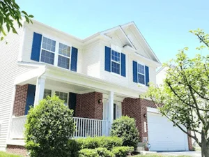 Two-story white house with navy shutters, freshly painted exterior siding and trim