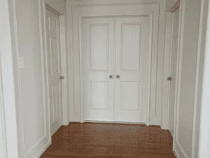 White painted entryway with double doors, trim, and vertical wall paneling