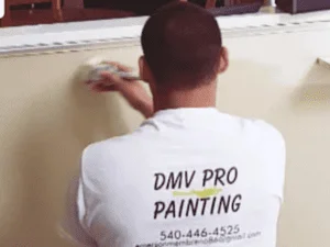 Painter applying interior wall paint with brush, professional technique