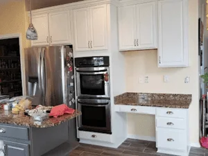 White painted kitchen cabinets and trim with stainless steel appliances and granite countertop