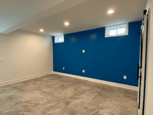 Deep blue accent wall with white walls, recessed lighting, and finished drywall in basement space